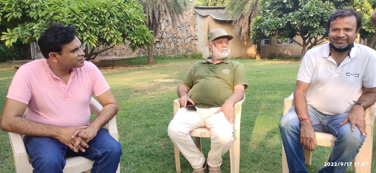 बिटटू बेकार seated in discussion with two colleagues on a lawn