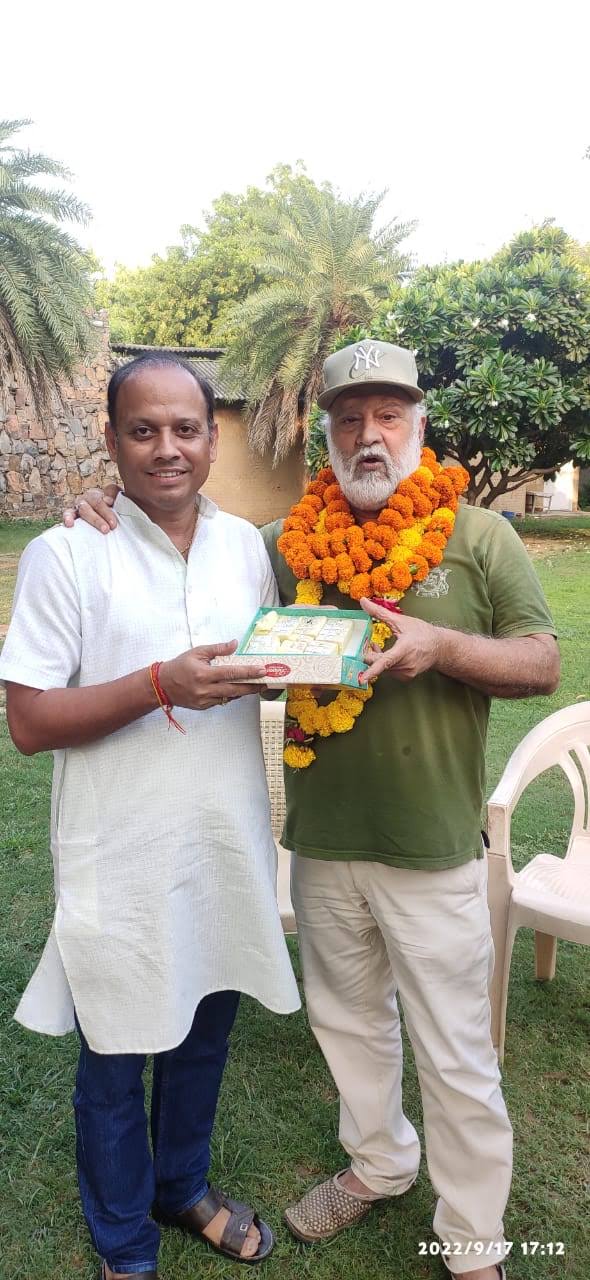 बिटटू बेकार garlanded and presented with a box of sweets by a colleague